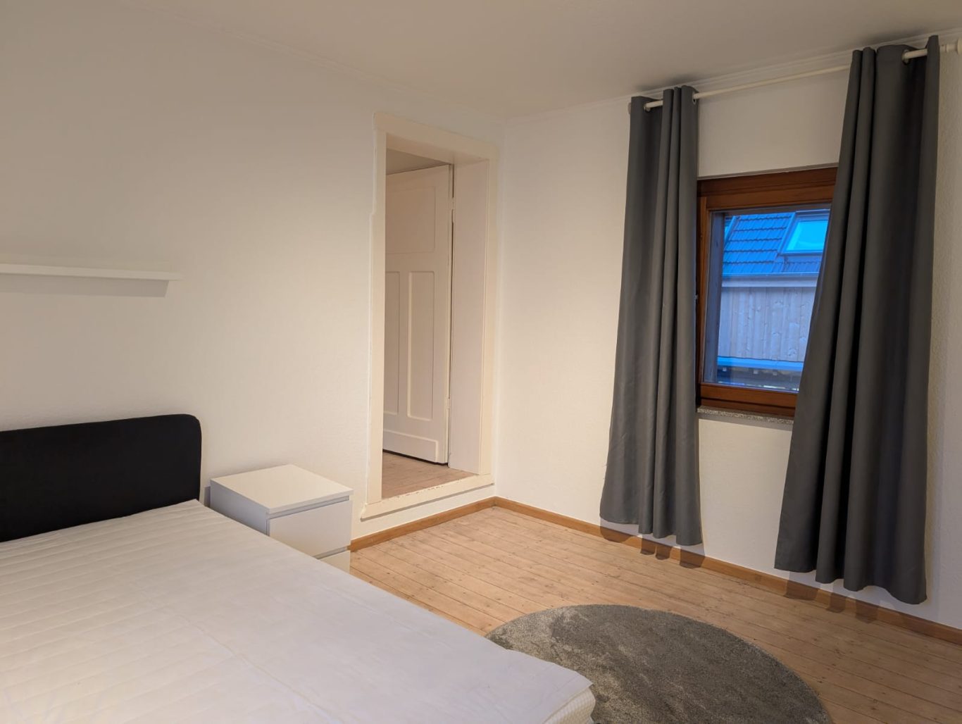 Zimmer 1 OG rechts Helles Schlafzimmer mit einem Bett, Vorhängen und einem Fenster.