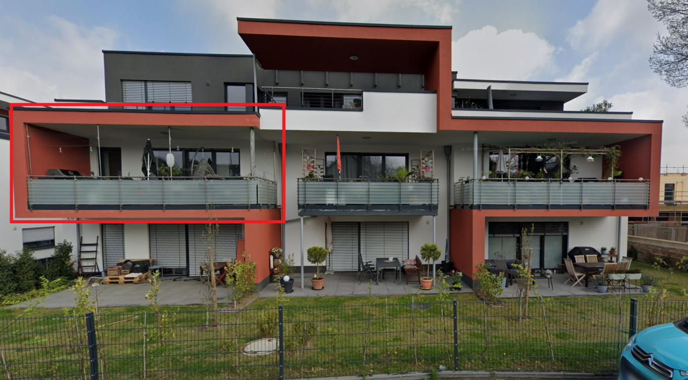 Immobilie straßenseitig Moderne Wohnanlage mit Balkon und Grünfläche im Vordergrund.