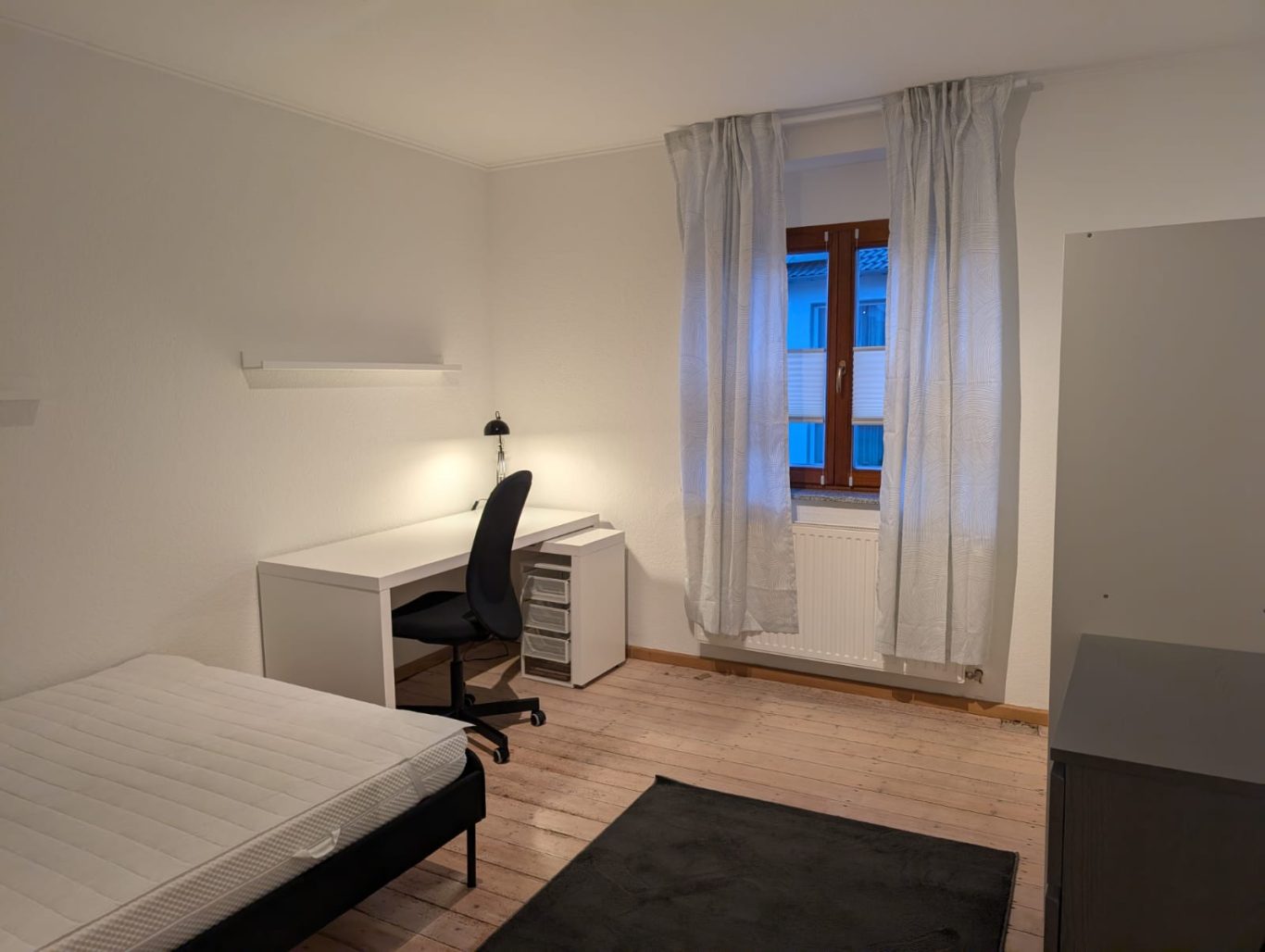 Zimmer OG links Helles Zimmer mit Schreibtisch, Stuhl, Bett und Fenster. Viel Platz und minimalistische Einrichtung.