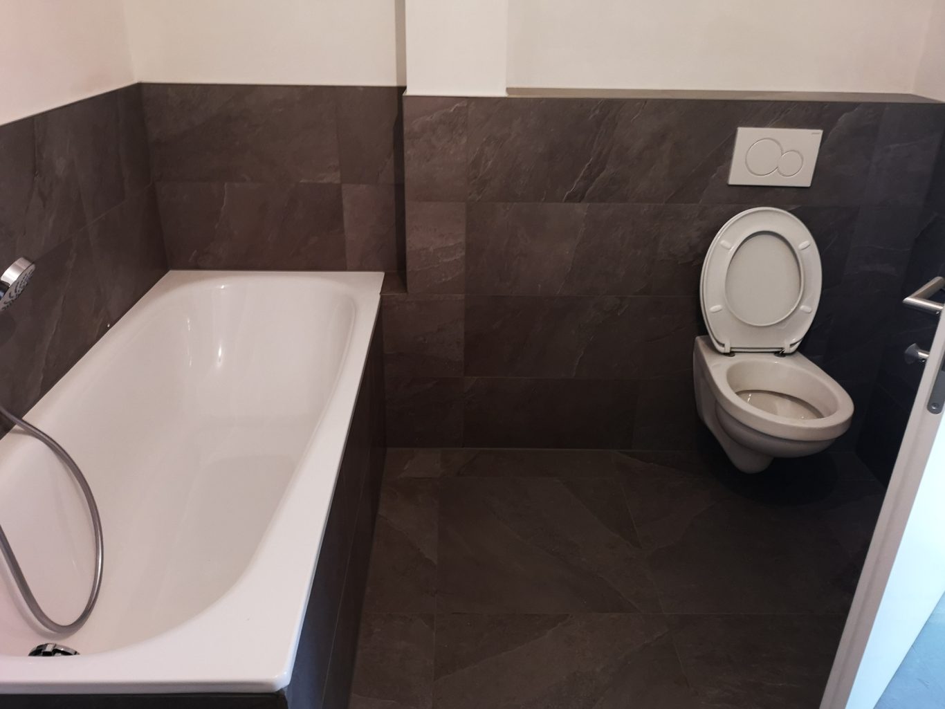 Bad rechts mit Wanne und Toilette Badezimmer mit Badewanne und Toilette auf einem modernen Fliesenboden.