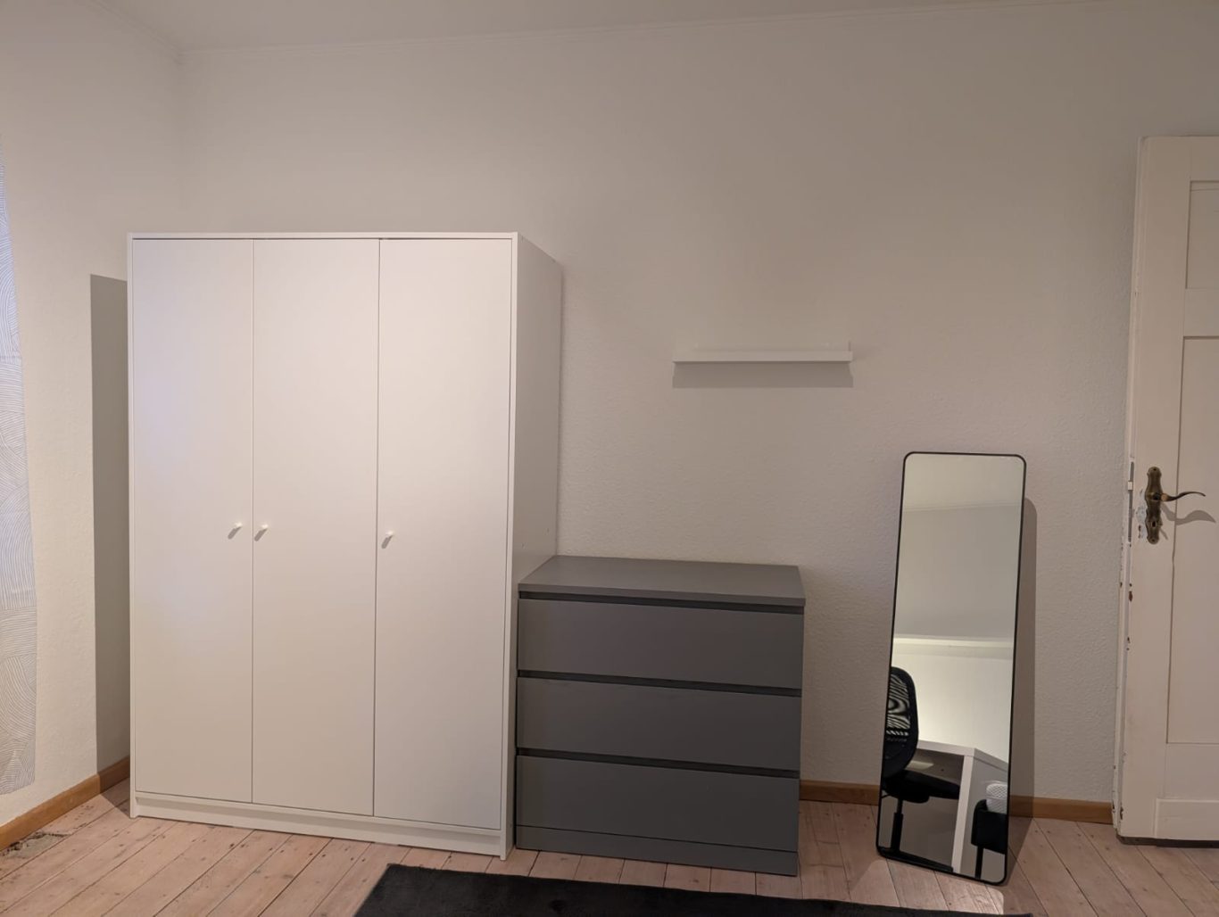 Zimmer OG links Raum mit einem weißen Kleiderschrank, grauem Kommode und einem Spiegel.
