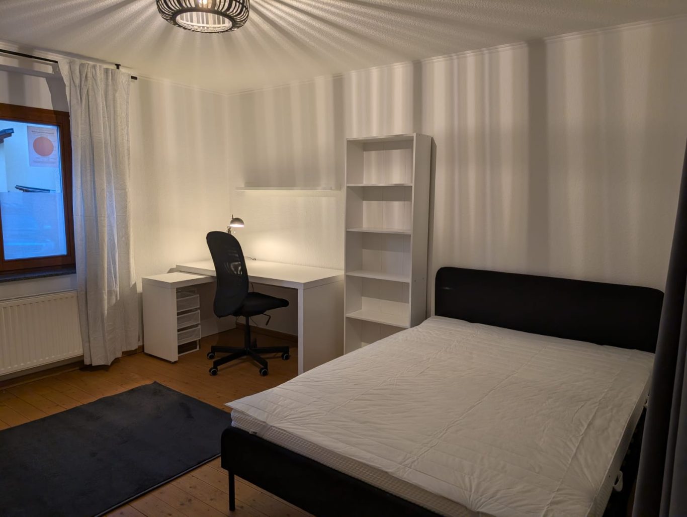 Zimmer EG rechts Heller, minimalistischer Raum mit Bett, Schreibtisch und Bücherregal.