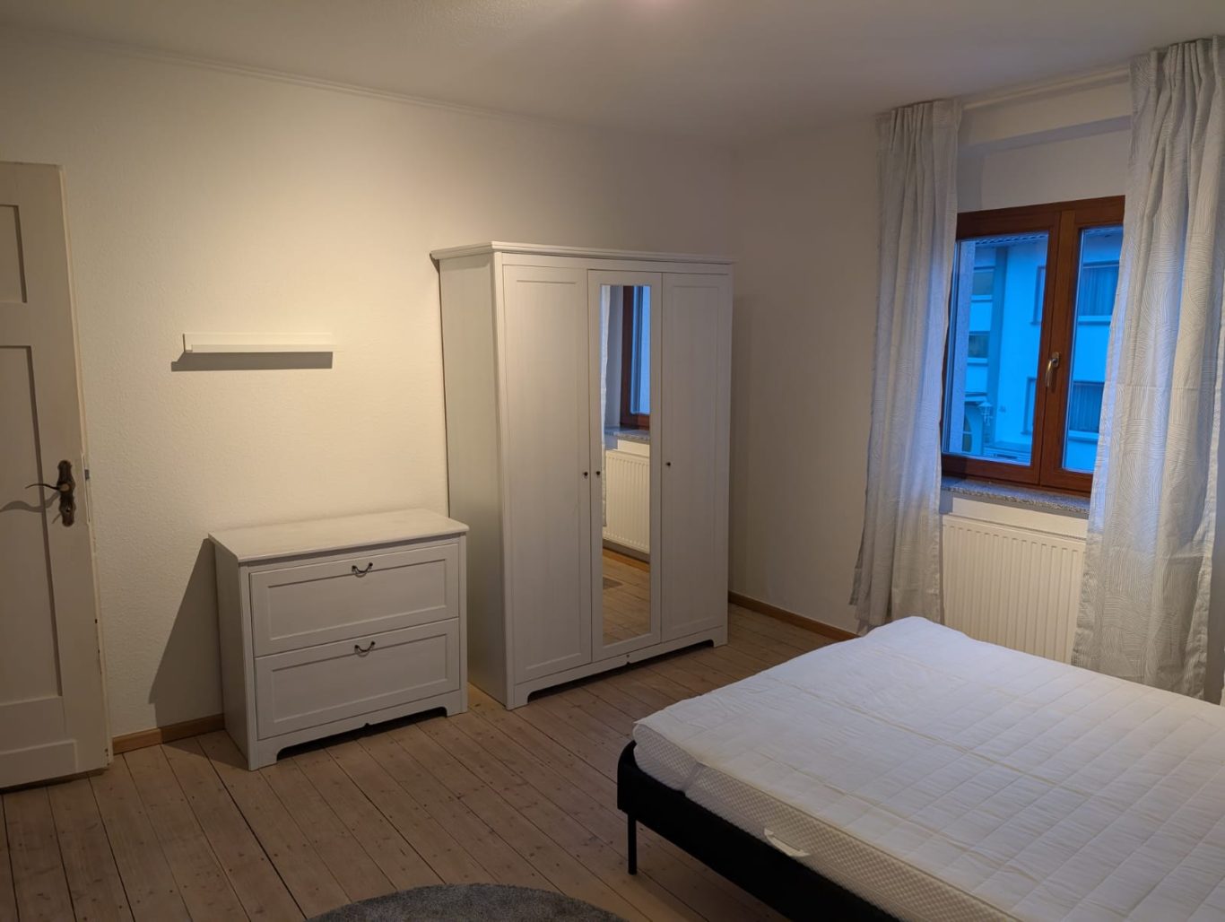 Zimmer 1 OG rechts Helles Schlafzimmer mit einem Bett, einem Kleiderschrank und einer Kommode.